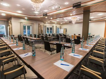 Seminarraum mit zahlreichen Plätzen vorbereitet mit Getränken und Schreibutensilien 