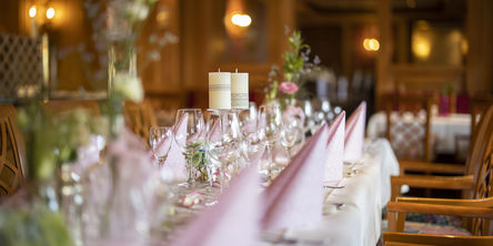 Langer gedeckter Tisch mit gefalteten Servietten, dekoriert mit Kerzen und Blumensträußen 
