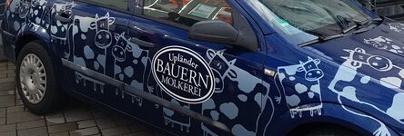 Blaues Auto der Upländer Bauern Molkerei mit aufgedruckten Kühen