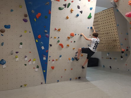 Jugendlicher klettert frei an einer Kletterwand