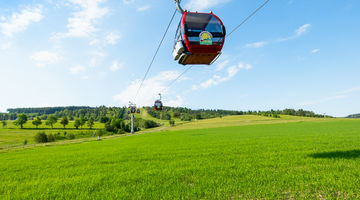 Kabinenbahn zum Ettelsberg über einer grünen Wiese