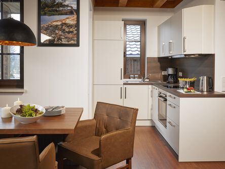 Moderne helle Küche mit Essbereich augestattet mit Lederstühlen an einem Holztisch 