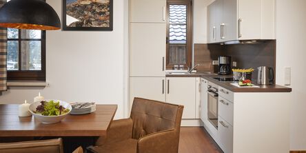 Moderne helle Küche mit Essbereich augestattet mit Lederstühlen an einem Holztisch 