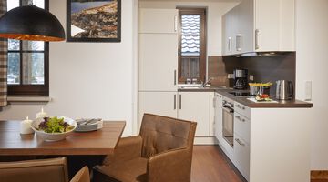Moderne helle Küche mit Essbereich augestattet mit Lederstühlen an einem Holztisch 