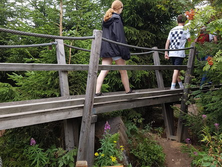 Eine Familie wandert über eine Holzbrücke