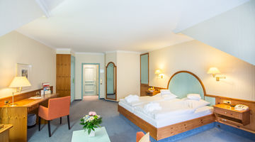 Einblick ins Zimmer mit Doppelbett gegenüber eines Holzschreibtisches