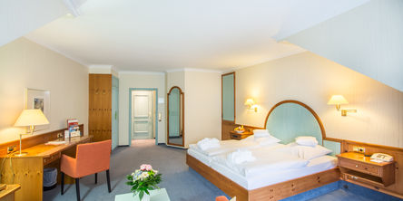 Einblick ins Zimmer mit Doppelbett gegenüber eines Holzschreibtisches