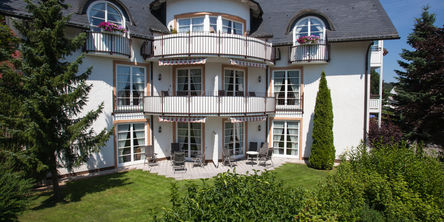 Außenansicht der Villa Katharina mit zwei großen Tannen im Garten 
