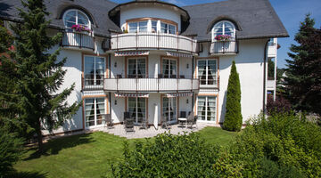Außenansicht der Villa Katharina mit zwei großen Tannen im Garten 