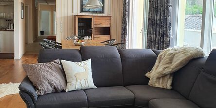 Wohn- und Essbereich des Alm Lofts mit dunkler Couch vor einem Esstisch mit vier Stühlen 