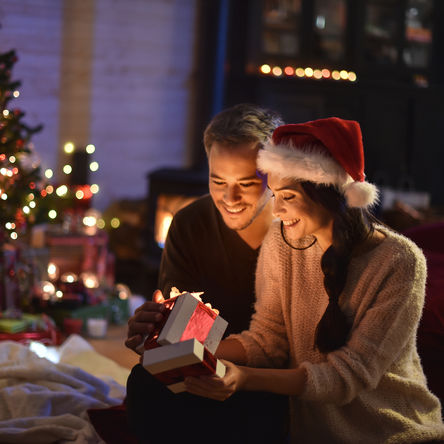 Paar öffnet die Geschenke neben einem Weihnachtsbaum 