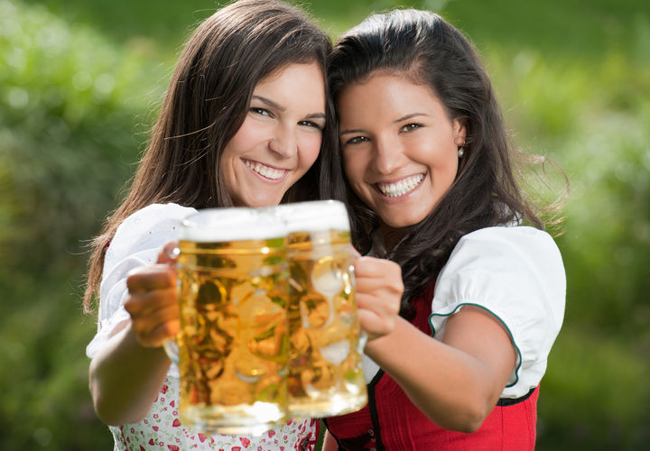 Zwei frauen im Dirndl stoßen mit Bier an