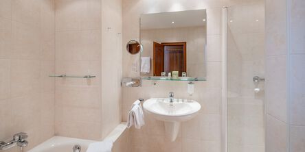 Helles Badezimmer mit Badewanne und einem Vergrößerungsspiegel neben dem Badezimmerspiegel