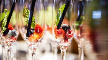 Sektgläser mit Beeren, Strohhalmen und Minzblätter