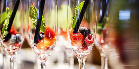 Sektgläser mit Beeren, Strohhalmen und Minzblätter