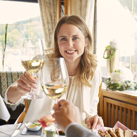 Frau stößt mit einem Glas Weißwein an 