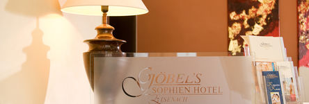 Schild mit Logo des "Göbel's Sophien Hotel Eisenach" aus Milchglas auf dem Tresen der Rezeption