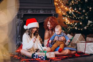 Mutter mit Baby und Kind beim Weihnachtsgeschenke auspacken