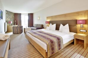 Einblick in das lichtdurchflutete Zimmer mit gemütlichem Doppelbett neben einem Sofa und einer Couch 