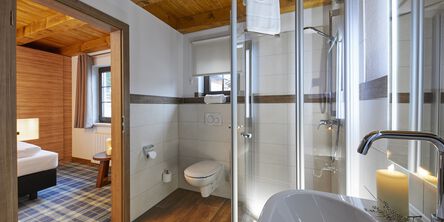 Helles Badezimmer mit weißer Kerze am Waschbecken neben der Dusche 