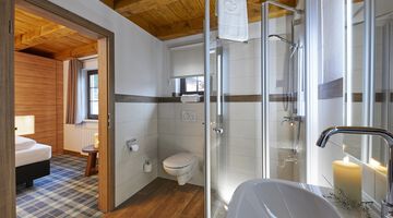 Helles Badezimmer mit weißer Kerze am Waschbecken neben der Dusche 