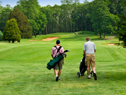 Zwei Männer mit Golfausrüstung auf einem Golfplatz