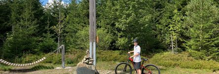 Junge steht mit seinem Fahrrad an einer Holzhängematte im Wald 