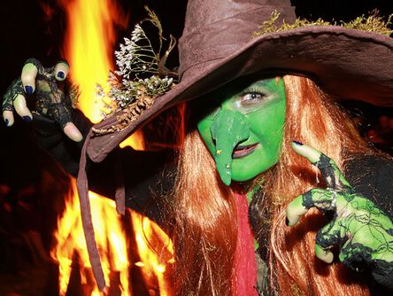 Frau als Hexe verkleidet vor einem Feuer bei der Walpurgisnacht