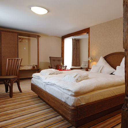 Rustikales Schlafzimmer in der Dorfalm mit dunklen Holzmöbeln und Holzbalken 