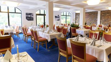 Das "Seaside" Restaurant am Diemelsee mit gedeckten Tischen und zahlreichen Sitzplätzen sowie blauem Teppichboden.