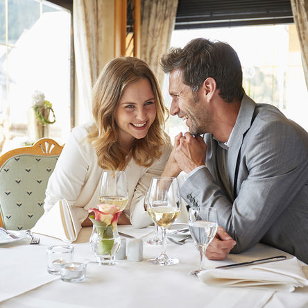 Lachendes Paar hält Händchen und sitzt an einem Tisch in einem Restaurant 