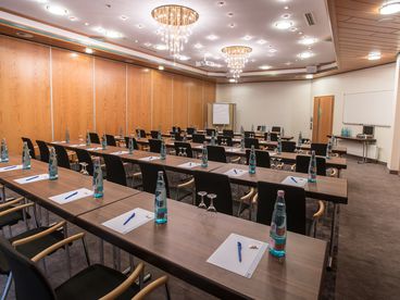 Tagungsraum mit Tischen, auf denen Blöcke, Stifte und Getränke stehen 