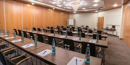 Tagungsraum mit Tischen, auf denen Blöcke, Stifte und Getränke stehen 