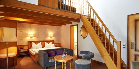 Familien-Maisonettezimmer mit einem Doppelbett und einer Holztreppe