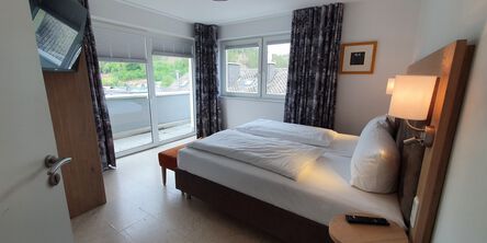 Schlafzimmer im Almloft mit Doppelbett und Zugang zum Balkon 