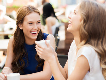 Zwei Freundinnen genießen einen entspannten Auszeit bei einer Tasse Cappuccino.