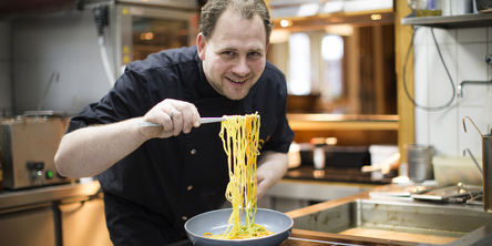 Koch hält bunte Spaghetti in die Kamera