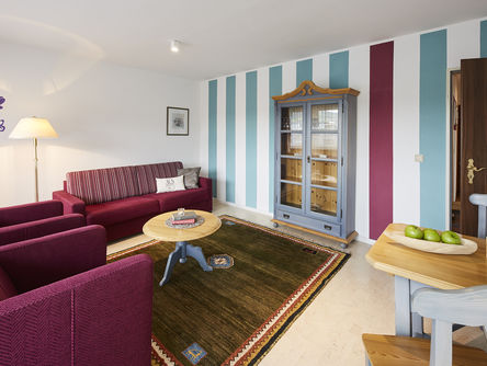 Loungebereich im Landhausstil mit hellblau und lila gestreifter Tapete und lilafarbenen Loungemöbeln 