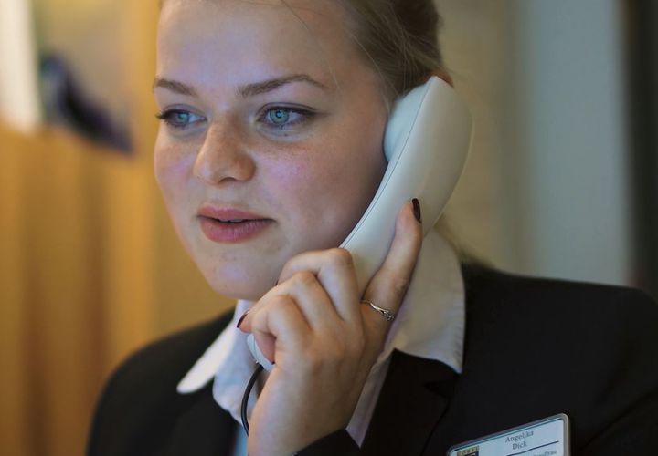 Hotel-Auszubildende telefoniert am Empfang.