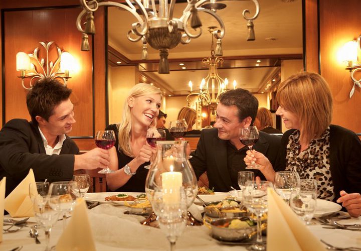 Zwei Paare stoßen bei einem Dinner mit Rotwein an 