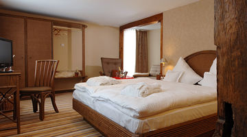 Rustikales Schlafzimmer in der Dorfalm mit dunklen Holzmöbeln und Holzbalken 