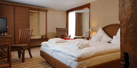 Rustikales Schlafzimmer in der Dorfalm mit dunklen Holzmöbeln und Holzbalken 