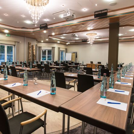 Großer Tagungsraum mit vielen Tischen, Beamer und Rednerpodest 
