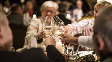 Vier Personen stoßen mit Weißwein an 