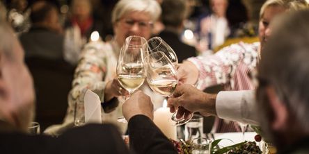 Vier Personen stoßen mit Weißwein an 