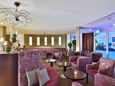 Hotellobby mit rot gemusterten Stühlen und Bänken 