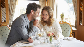 Lachendes Paar hält Händchen und sitzt an einem Tisch in einem Restaurant 