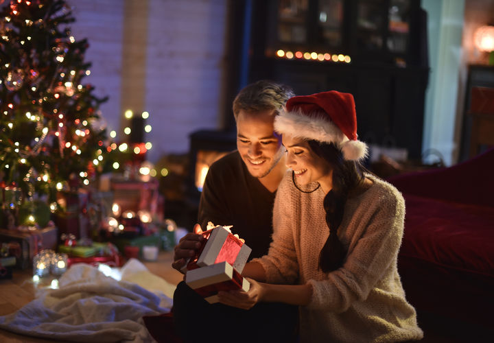 Paar öffnet die Geschenke neben einem Weihnachtsbaum 