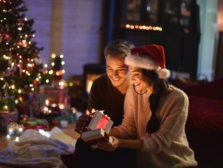Paar öffnet die Geschenke neben einem Weihnachtsbaum 