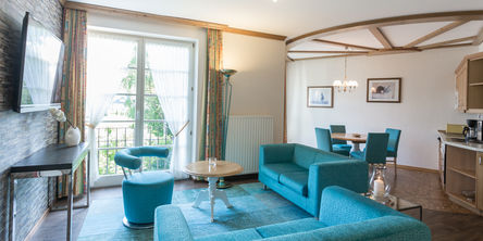 Helles Wohnzimmer mit zwei blauen Sofas und einem passendem Sessel neben einem Fenster